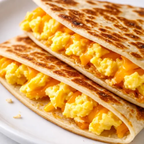 Golden brown crispy cheddar eggs quesadilla on a plate with melted cheese and egg filling, perfect for quick meals.