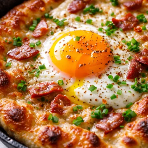 Golden crispy breakfast pizza with melted cheese, crispy bacon, and a perfectly runny egg center, garnished with chives.