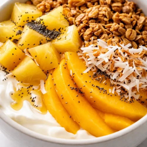 Creamy yogurt granola bowl topped with crunchy granola clusters, fresh blueberries, and a drizzle of honey on a white ceramic bowl.