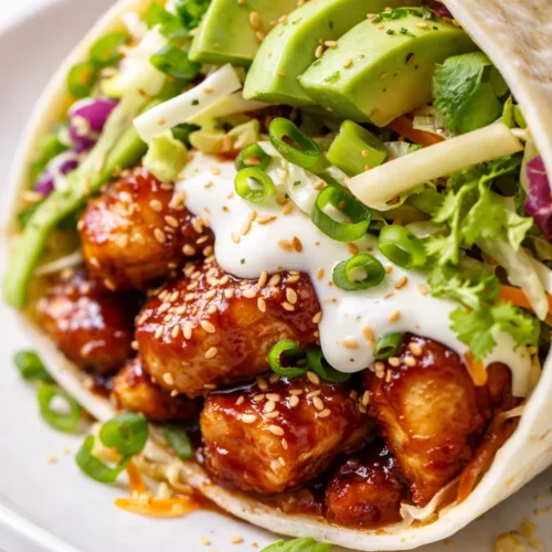 Golden flour tortilla filled with fluffy scrambled eggs, seasoned black beans, melted cheddar cheese, and creamy avocado slices, with a small dish of salsa verde on the side