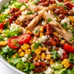 Vibrant spicy Southwest chicken salad with grilled chicken, black beans, corn, avocado, and cherry tomatoes, drizzled with creamy chipotle dressing, showing crisp textures and fresh colors.