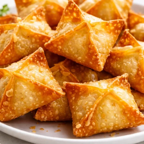 Crispy golden brown air fryer cream cheese wontons arranged on a plate, showing no leaks or sogginess.