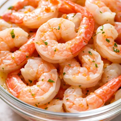 Vibrant shrimp ceviche in a glass bowl with fresh cilantro, diced avocado, and red onion, marinated in citrus juices – bright and fresh.