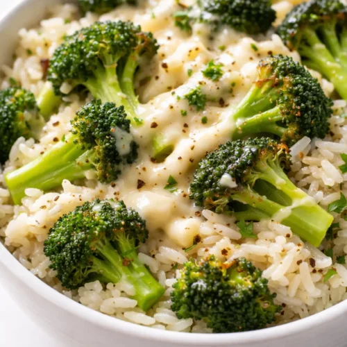 Creamy broccoli cheddar rice in a white bowl, with tender broccoli florets and melted cheddar cheese, not mushy.