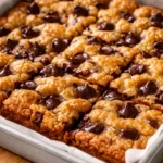 Golden brown chewy chocolate chip cookie bars with gooey chocolate chips, slightly crispy edges and soft center, cut into squares on a cooling rack.