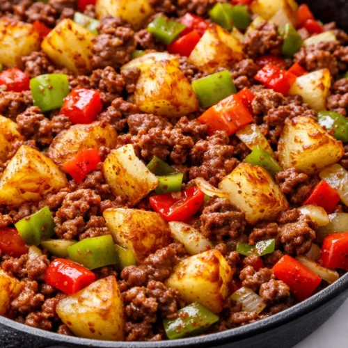 Savory cowboy stir fry with seasoned beef, colorful peppers, and onions in a cast iron skillet, hearty and golden brown.