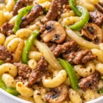 Easy high-protein Philly cheesesteak macaroni and cheese with melted provolone, tender steak strips, and colorful bell peppers in a creamy, golden baked dish.
