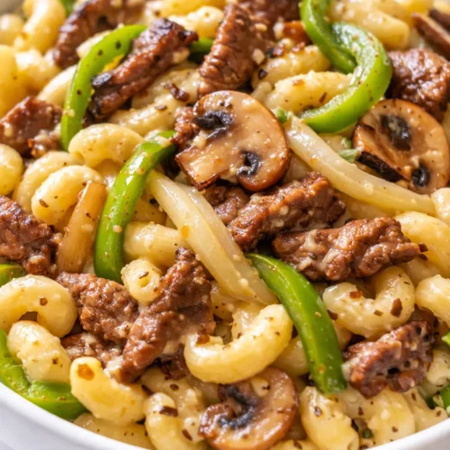 Easy high-protein Philly cheesesteak macaroni and cheese with melted provolone, tender steak strips, and colorful bell peppers in a creamy, golden baked dish.