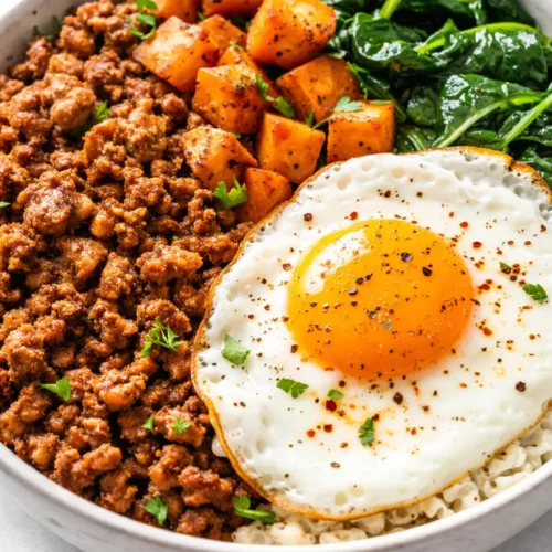 A hearty healthy turkey breakfast bowl loaded with scrambled eggs, diced turkey breast, creamy avocado, and juicy cherry tomatoes, topped with fresh cilantro for a colorful and nutritious start.