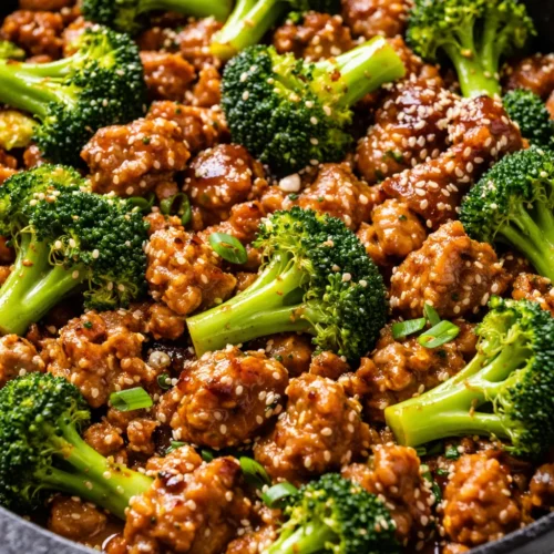 Juicy honey garlic ground turkey in a skillet with a glossy, sticky sauce, garnished with sliced green onions and sesame seeds.