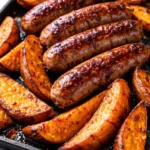 Golden brown sausages and caramelized sweet potatoes on a sheet pan, glazed with honey garlic sauce, creating a crispy and savory dinner.