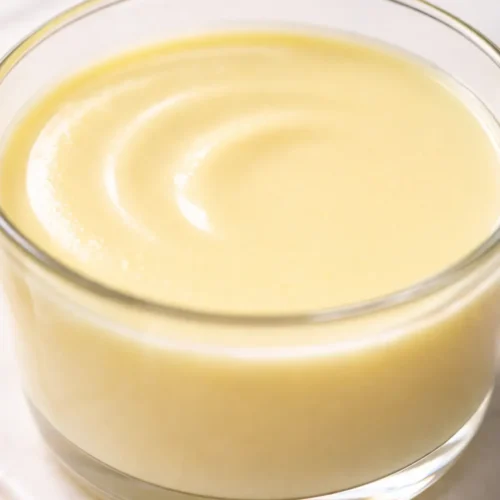 Smooth, creamy lemon posset with silky texture and bright yellow color, perfectly set without curdling.