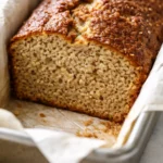 Moist low calorie banana bread slice with golden brown crust and tender crumb, studded with banana chunks.
