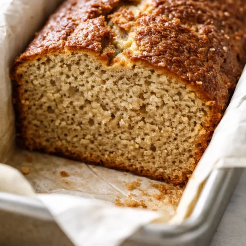 Moist low calorie banana bread slice with golden brown crust and tender crumb, studded with banana chunks.