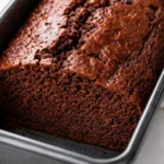 Moist gluten free chocolate banana bread slice with melted chocolate chips, rich brown crumb, and visible banana flecks.