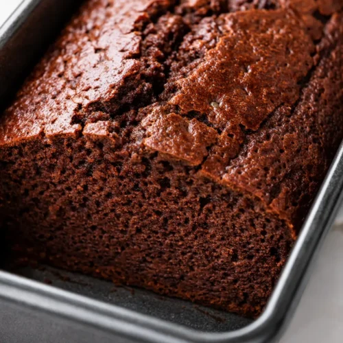 Moist gluten free chocolate banana bread slice with melted chocolate chips, rich brown crumb, and visible banana flecks.