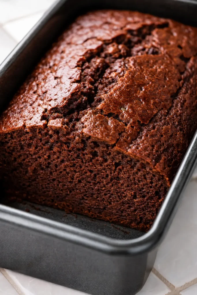 Moist gluten free chocolate banana bread slice with melted chocolate chips, rich brown crumb, and visible banana flecks.