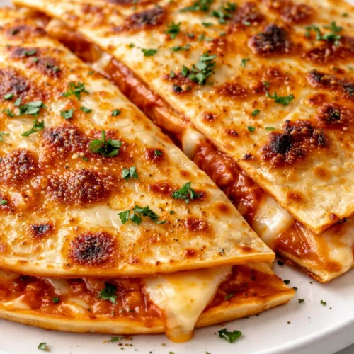 Crispy pizza quesadilla slices with melted mozzarella, pepperoni, and golden brown tortilla on a plate.