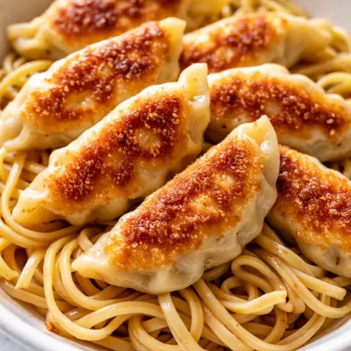 Potsticker noodle bowls with crispy potstickers, tender noodles, glossy soy sauce, and vibrant green onions.