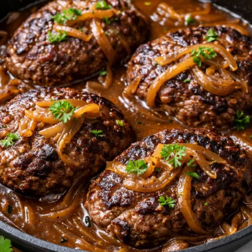 Smothered hamburger steaks with rich brown gravy, topped with caramelized onions, served over creamy mashed potatoes.