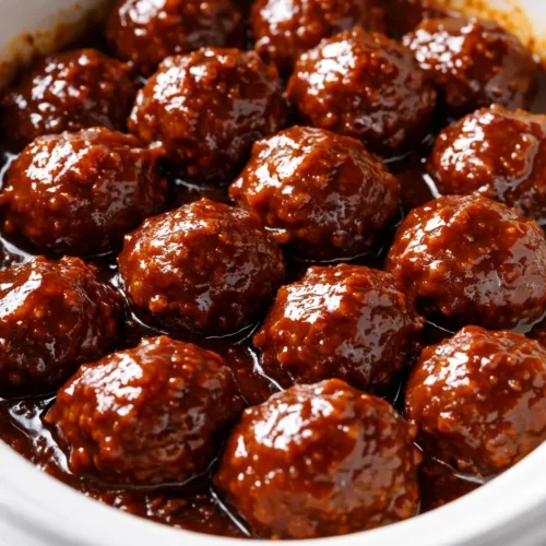 A platter of tropical BBQ meatballs glazed with sticky-sweet sauce, garnished with pineapple chunks and green onions, with a glossy, caramelized sheen.