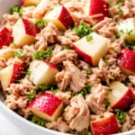 Matthew McConaughey's tuna apple salad with crisp apple chunks, flaked tuna, and creamy dressing on a plate, garnished with fresh herbs.