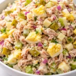 Creamy tuna egg salad with crunchy pickle bits and egg chunks, served in a bowl.