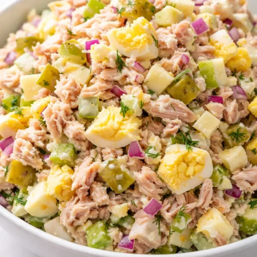 Creamy tuna egg salad with crunchy pickle bits and egg chunks, served in a bowl.