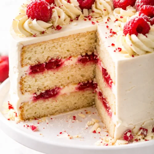 White chocolate raspberry dream cake with creamy white chocolate frosting, fresh raspberries, and visible cake layers.
