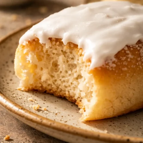 Soft pillowy iced buns with glossy white icing and a bright red cherry on top, showing fluffy texture