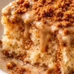 Rich cookie butter tres leches cake slice with creamy soaked sponge and crumbly Biscoff topping on a white plate