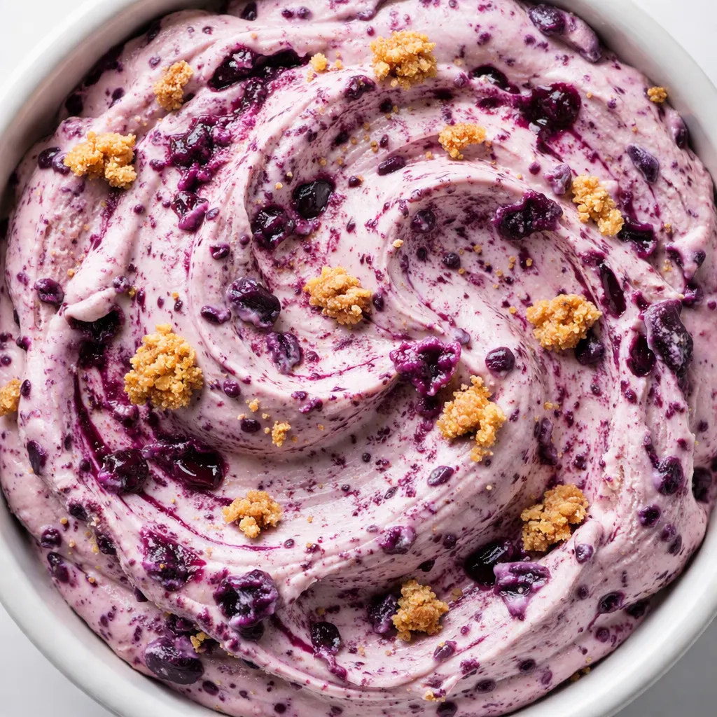 Smooth purple-blue blueberry cheesecake protein ice cream mixture being poured into a Ninja Creami pint container