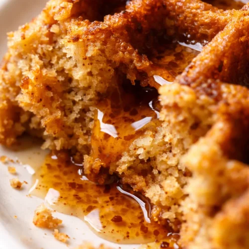 Golden brown crispy gluten-free pumpkin waffles made with almond flour, topped with butter and maple syrup on a white plate