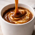 Rich amber pumpkin marshmallow coffee syrup in a glass jar, warm and creamy with cinnamon and fall spices