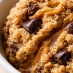 Creamy thick protein cookie dough with chocolate chips on a white plate, showing a smooth and scoopable texture