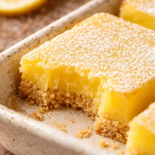 Golden lemon bars with crisp buttery shortbread crust and smooth tangy lemon curd, topped with powdered sugar