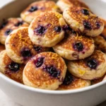 Golden fluffy Greek yogurt pancake bites studded with blueberries and drizzled with lemon glaze, served on a plate