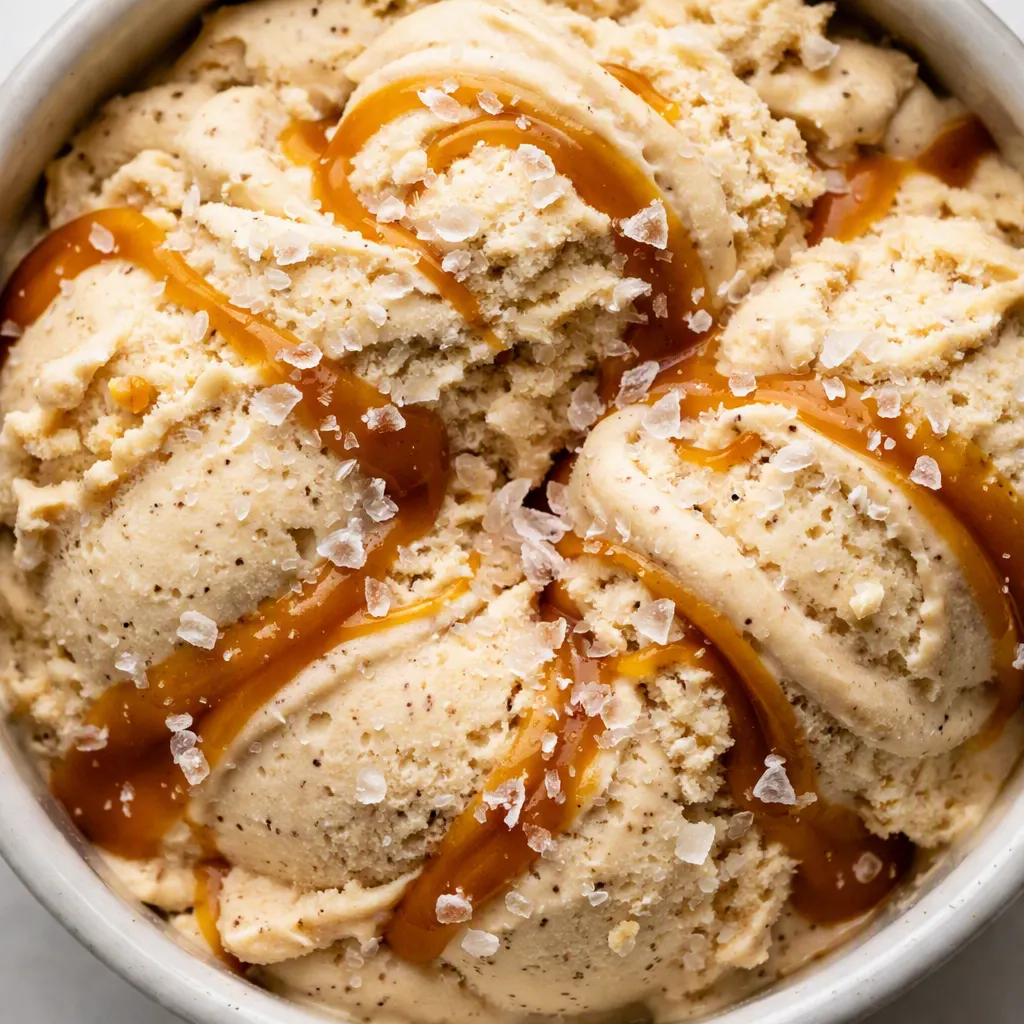 Pouring smooth salted caramel protein ice cream base into a Ninja Creami pint, showing creamy pale brown liquid