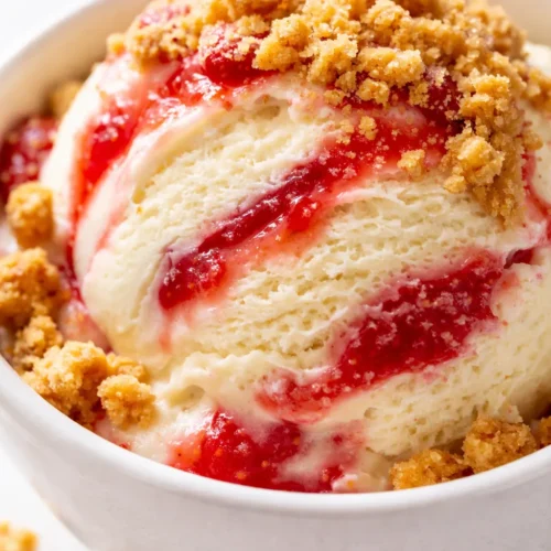 Tangy, creamy Ninja Creami strawberry cheesecake ice cream topped with brown butter graham crumble, pink and white swirls with golden crumble bits.