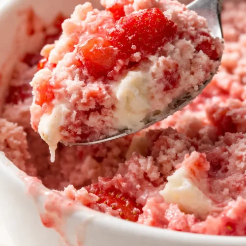 Creamy scoop of homemade Ninja Creami strawberry ice cream in a white bowl, soft pink with visible strawberry flecks