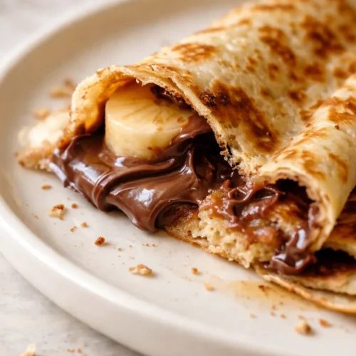 Golden crepes drizzled with melted Nutella and topped with sliced bananas, creamy and decadent