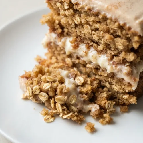 Golden oatmeal cream pie cake slice with creamy white filling and crumbly oat streusel on top