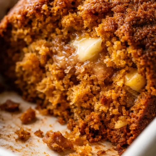 Moist pumpkin bread slice with golden-brown crust, showing tender crumb texture on a white plate