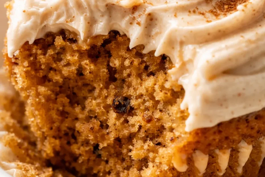 Swoops of brown sugar cream cheese frosting atop moist pumpkin cupcakes on a rustic wooden stand, dusted with cinnamon