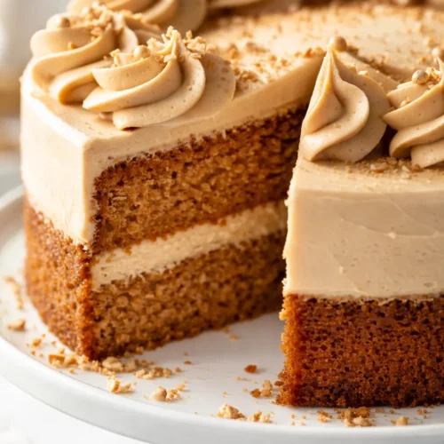 A slice of tender brown sugar cake with silky coffee buttercream and a glossy salted caramel drizzle on a white plate