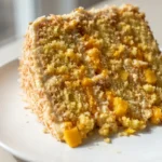 Golden crusted vegan mango coconut cake topped with silky mango buttercream and fresh mango slices, showing moist tender crumb
