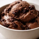 Creamy brownie batter protein ice cream in a bowl with chopped fudgy brownie chunks, rich chocolate color, and smooth thick texture