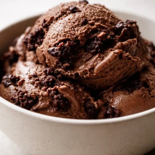 Creamy brownie batter protein ice cream in a bowl with chopped fudgy brownie chunks, rich chocolate color, and smooth thick texture