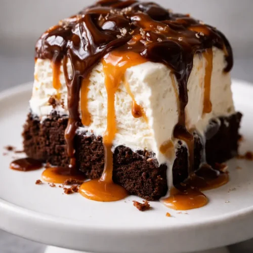 Easy brownie ice cream cake slice with fudgy brownie, creamy vanilla ice cream, Oreo chunks, and glossy hot fudge