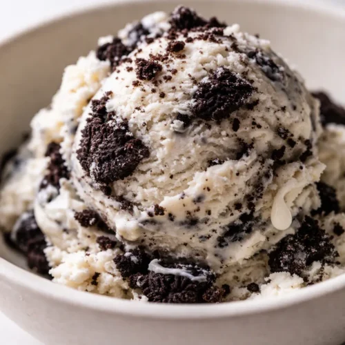Creamy Ninja Creami cookies and cream ice cream in a bowl, swirled with chocolate Oreo chunks and a smooth, velvety texture
